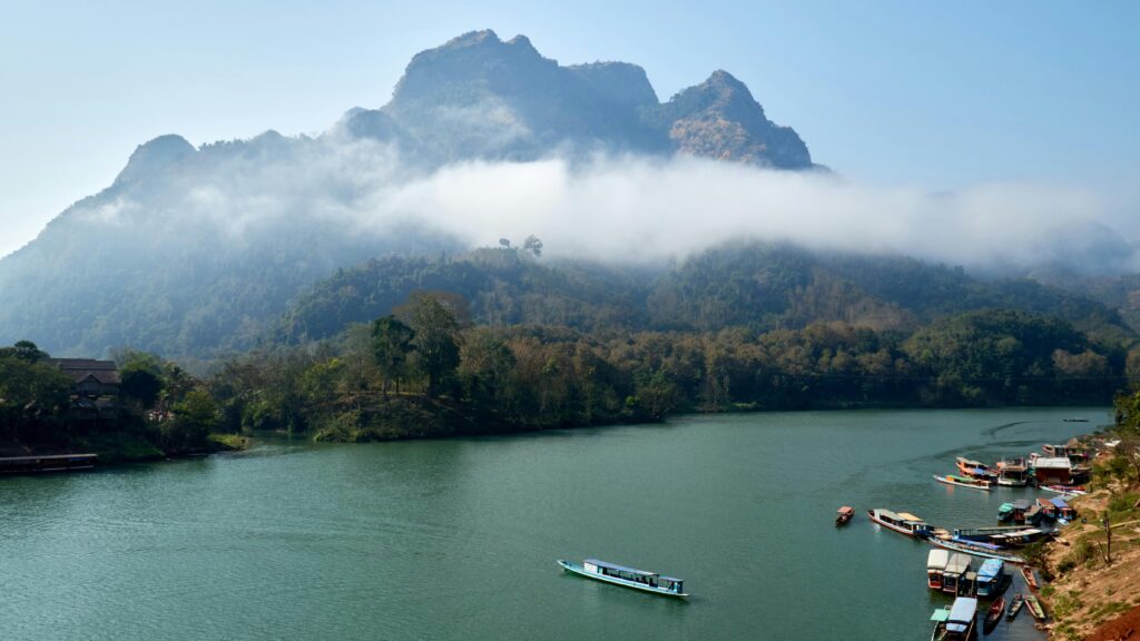 Breathtaking view of misty mountains and serene river in Nong Khiaw, Laos. Perfect for travel and nature enthusiasts.